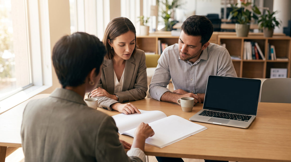 Two professionals reviewing a partnership document across a desk in a bright office, representing vetting a nonprofit partner for a checkout giving program.