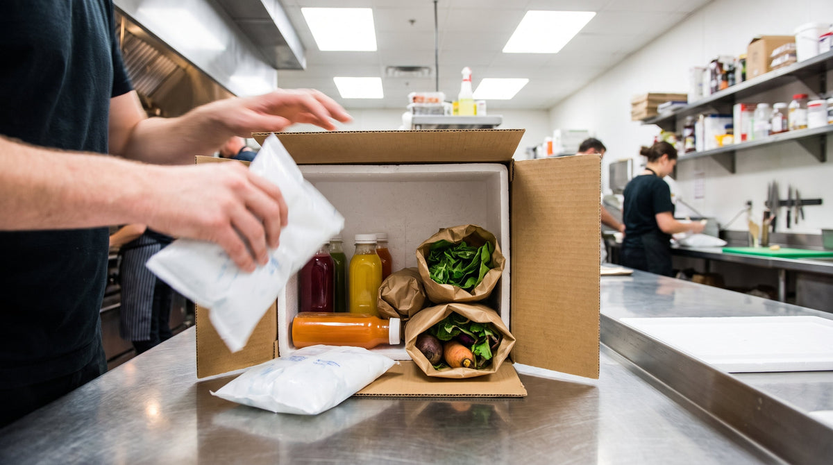An insulated food-and-beverage shipment being packed quickly on a prep table, representing fulfillment speed for DTC food brands.