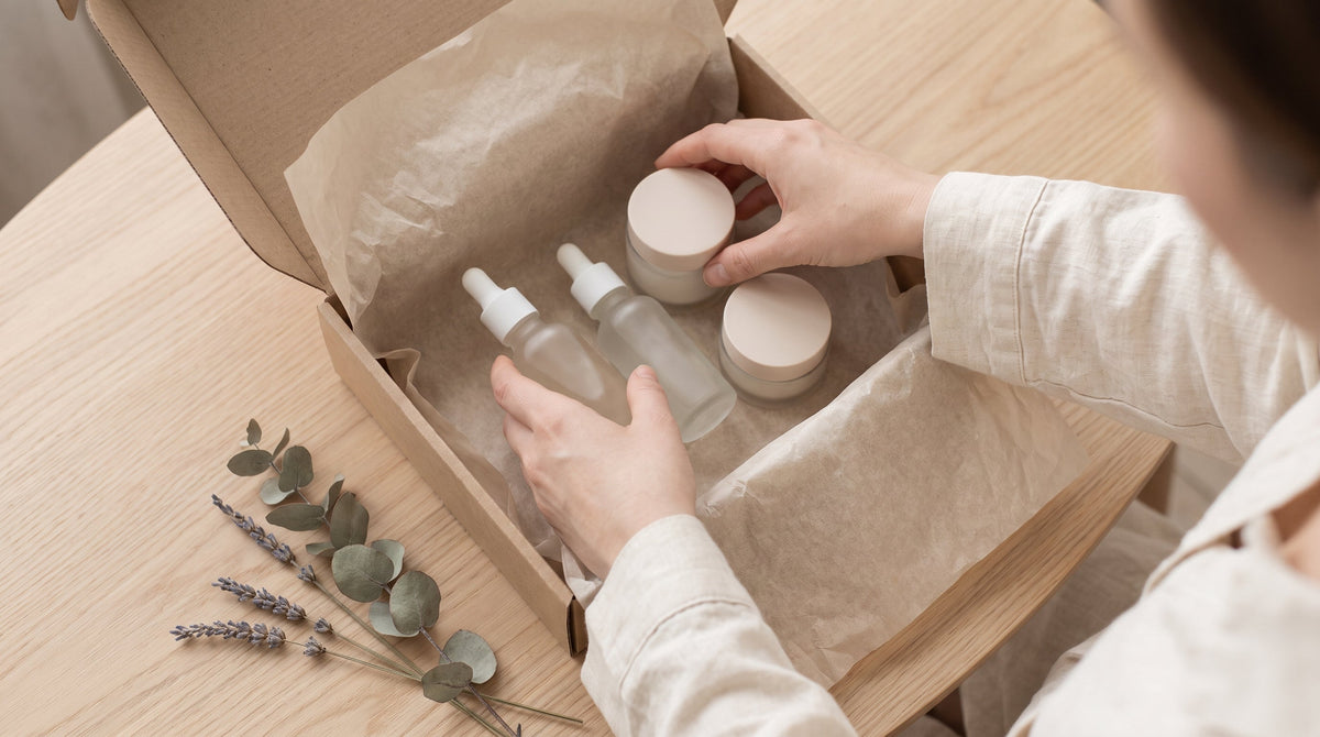 Skincare bottles and jars being packed into a shipping box, representing the post-purchase playbook for beauty and skincare brands.